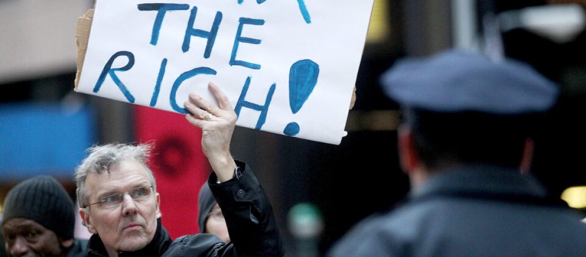 NEW YORK, NY - MARCH 24:  A protester holds a "Tax the Rich" sign as he marches during a rally against budget slashing held by union supporters on March 24, 2011 in New York City. The protesters called for closing tax loopholes for the wealthy and ending budget cuts for social programs. (Photo by Mario Tama/Getty Images)